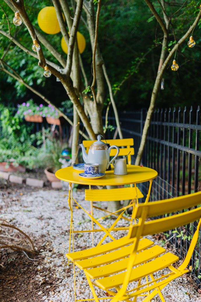 Lovely yellow outdoor table set provides seating in the garden-designaddictmom