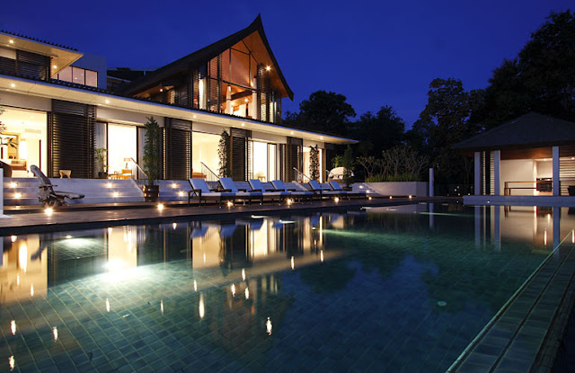 Photo of modern villa at night as seen from the pool