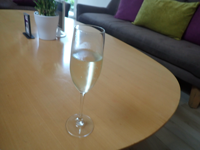 A light wood coffee table with a flute of sparkling wine