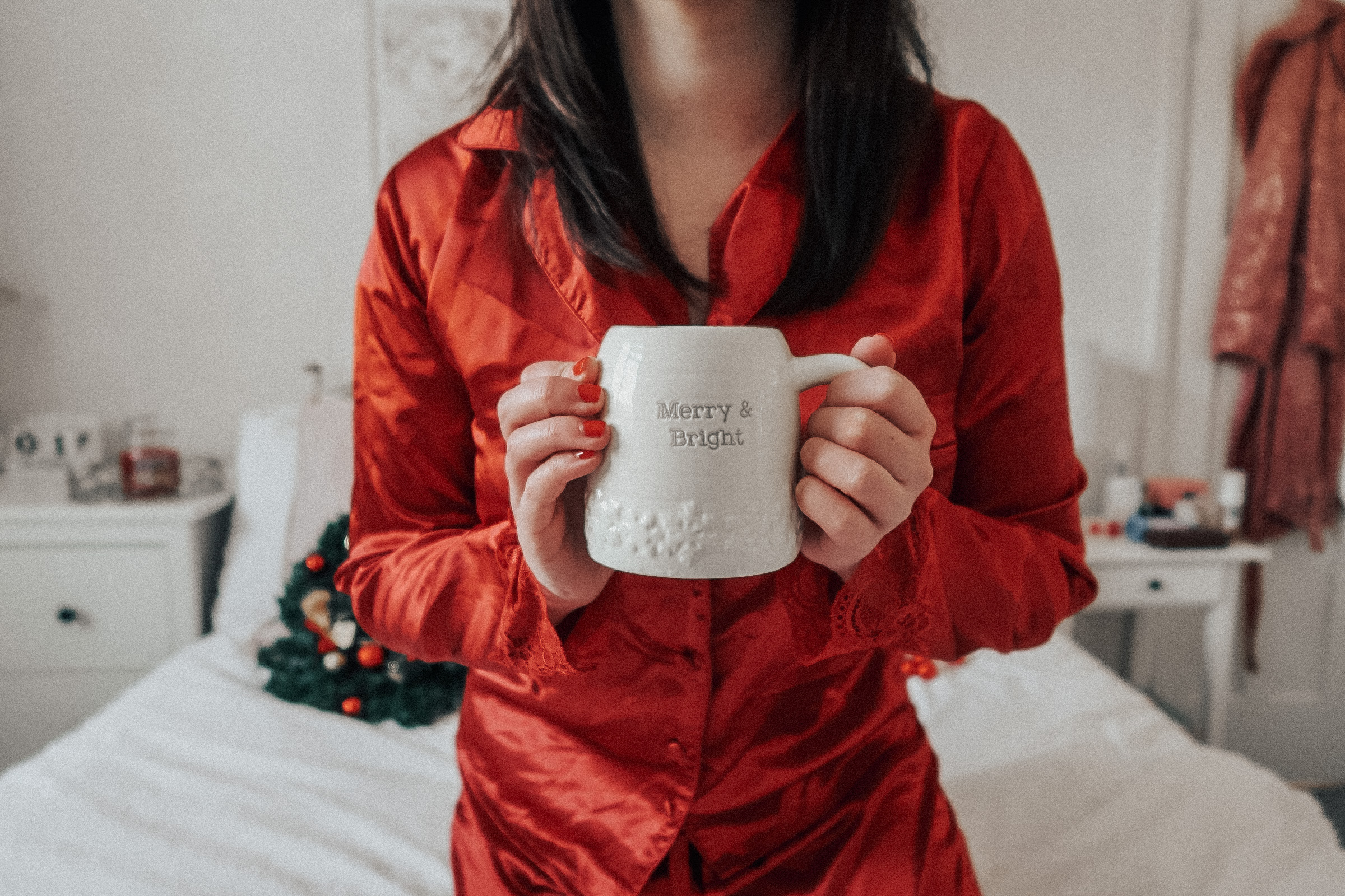 A woman holding a Christmas mug wearing red pyjamas