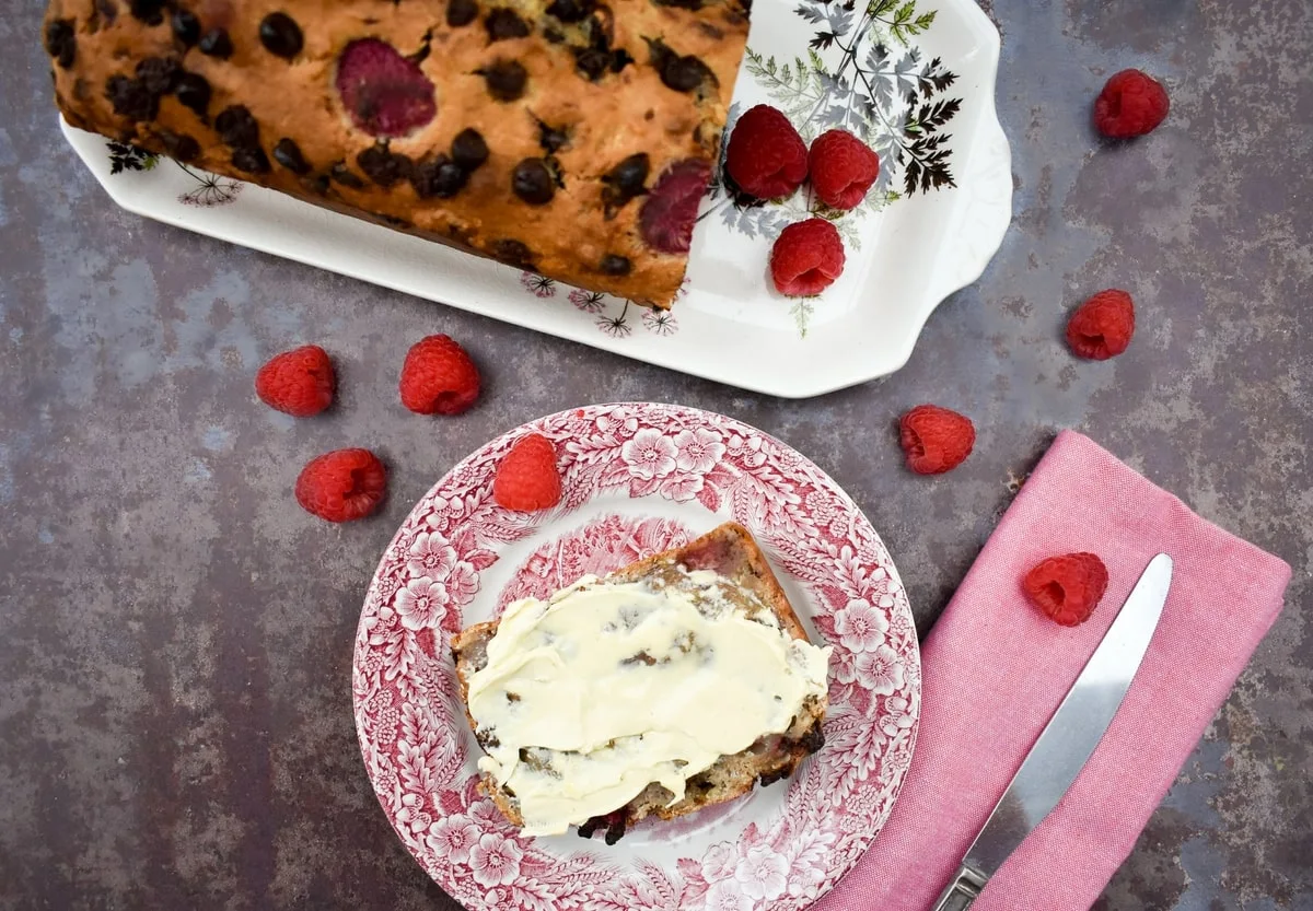 Easy homemade banana bread on a platter and a buttered slice on a teaplate.