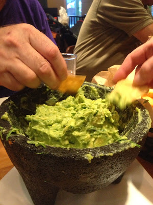 Bowl of guacamole with people dipping