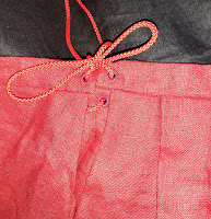 Red linen skirt side closure with a red cord threaded through 4 hand sewn eyelets, and tied in a bow