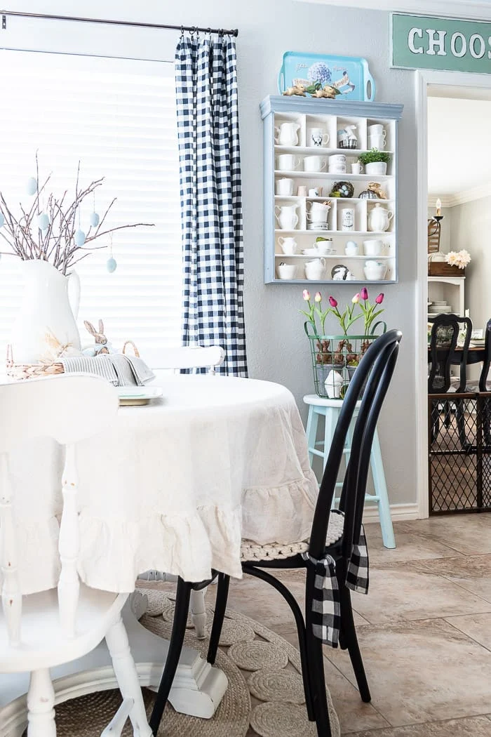 white and black chairs around round table, branches with Easter eggs