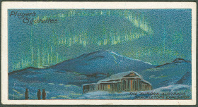 A card with an illustration of the northern lights over a snowy cabin.