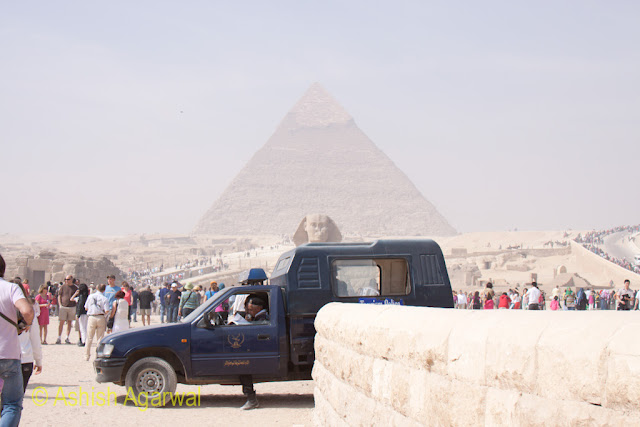 A police vehicle in front of The Sphinx and the Great Pyarmid in Giza