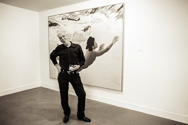 Photo of Theo Wujcik standing in front of a painting at Tempus Projects Art gallery