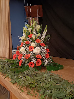 Escenario con centros florales y verdes para la presentación de la falla