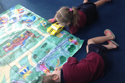 Two young children working with a robotic car and a map of a fair ground.