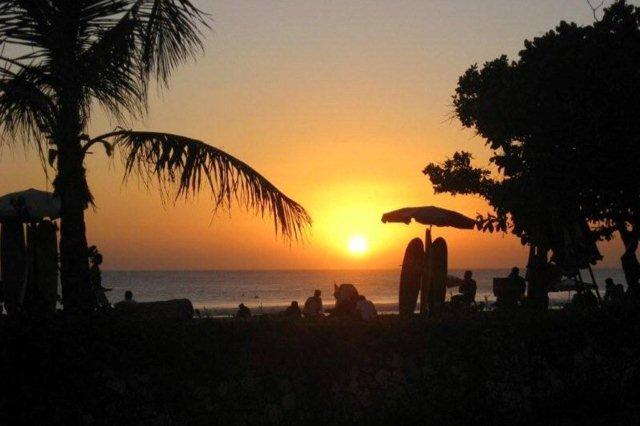 Atardecer, tablas de surf y palmeras. Playa Kuta Beach, Bali