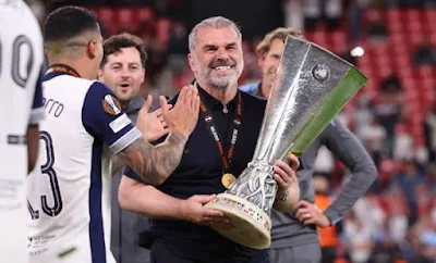 "Ange Postecoglou celebrates with the Europa Conference League trophy after Tottenham's victory"