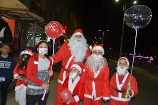 بابا نويل وأطفاله يوزعون الكمامات والهدايا علي المواطنين بمدينة إسنا جنوب الأقصر