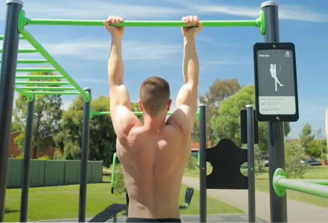 Muscular man doing chin-up exercises at outdoor