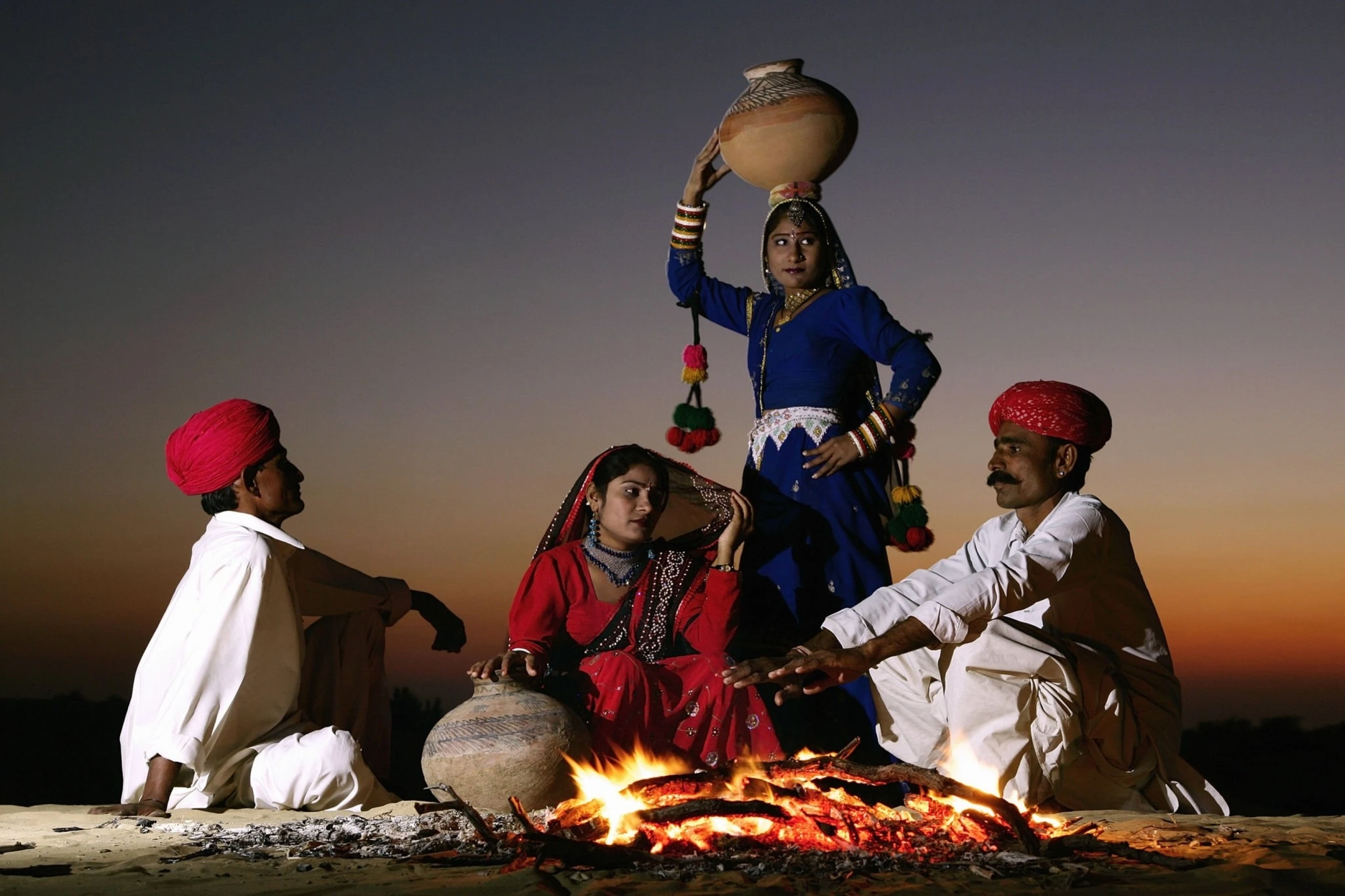 India, Rajasthan, Jaiselmer, Rajput tribesmen and women by campfire at twilight