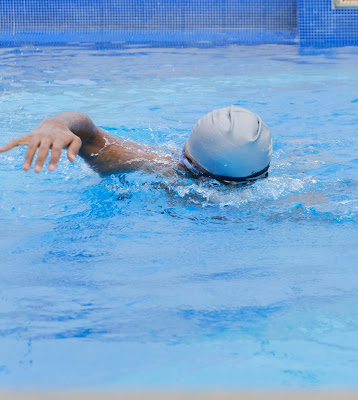 Picture of a person wearing a white swimming cap, swimming in the pool. Unlocking Possibility: Swimming & Individuals with Disabilities