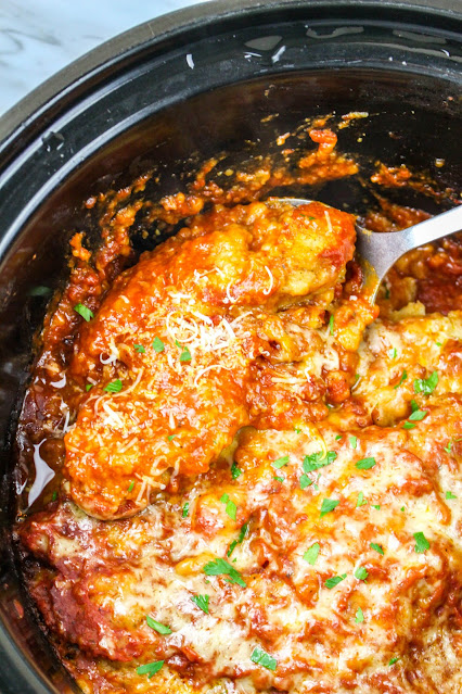 chicken in slow cooker with a spoon scooping it.