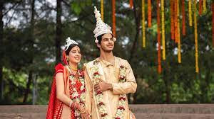 A girl in a red saree & red blouse and a boy in a light colored Kurta