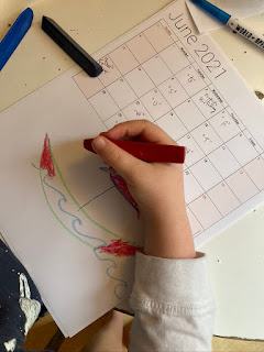 child drawing a boat at the bottom of a calendar page for june 2021