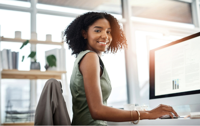 Woman smiling and turning away from her computer that has SPARCS compliance information on it.