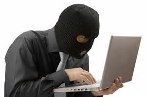 Male Employee in Black Ski Mask Hovers Over Laptop Stealing Confidential Information