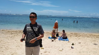 Wawan dengan latar turis yang berjemur di Pantai Pandawa Bali