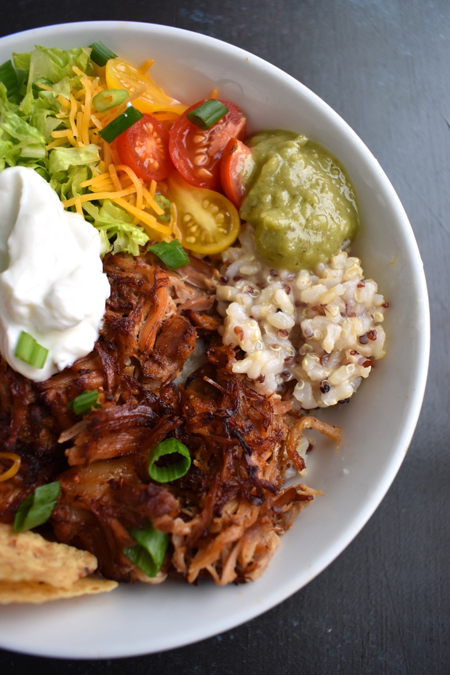 Carnitas Burrito Bowls feature crispy, flavorful pork carnitas, brown rice, cheddar cheese, tomato, green onion, chips, bell peppers and more for a fresh, filling meal ready in about 30 minutes! www.nutritionistreviews.com #mexicanfood #mexican #burrito #pork #dinner #easydinner