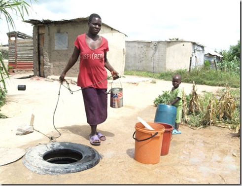 A woman draws water from a well at Hopley Farm, a  settlement on the outskirts of Harare, Zimbabwe, 24 March 2010.
Hopley was created under Operation Garikai in 2005 for people who lost their homes in Operation Muarambatsvina.
Thousands of people have lived for more than five years in Hopley settlement in makeshift plastic shacks, with little or no access to basic services such as water, sanitation, education and health care. 