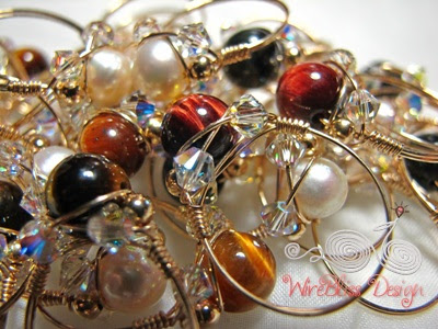 a bunch of wire wrapped sparkly rings with pearl and tiger eyes