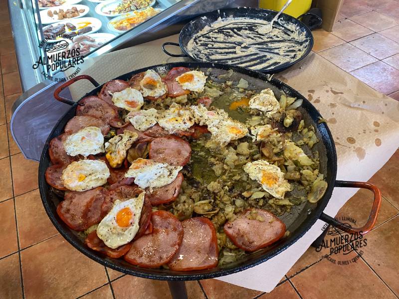 Paella con patatas fritas, lomo adobado, huevos fritos y ajos tiernos