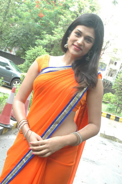 Shraddha Das looking radiant in an orange sleeveless saree, exuding elegance and grace.
