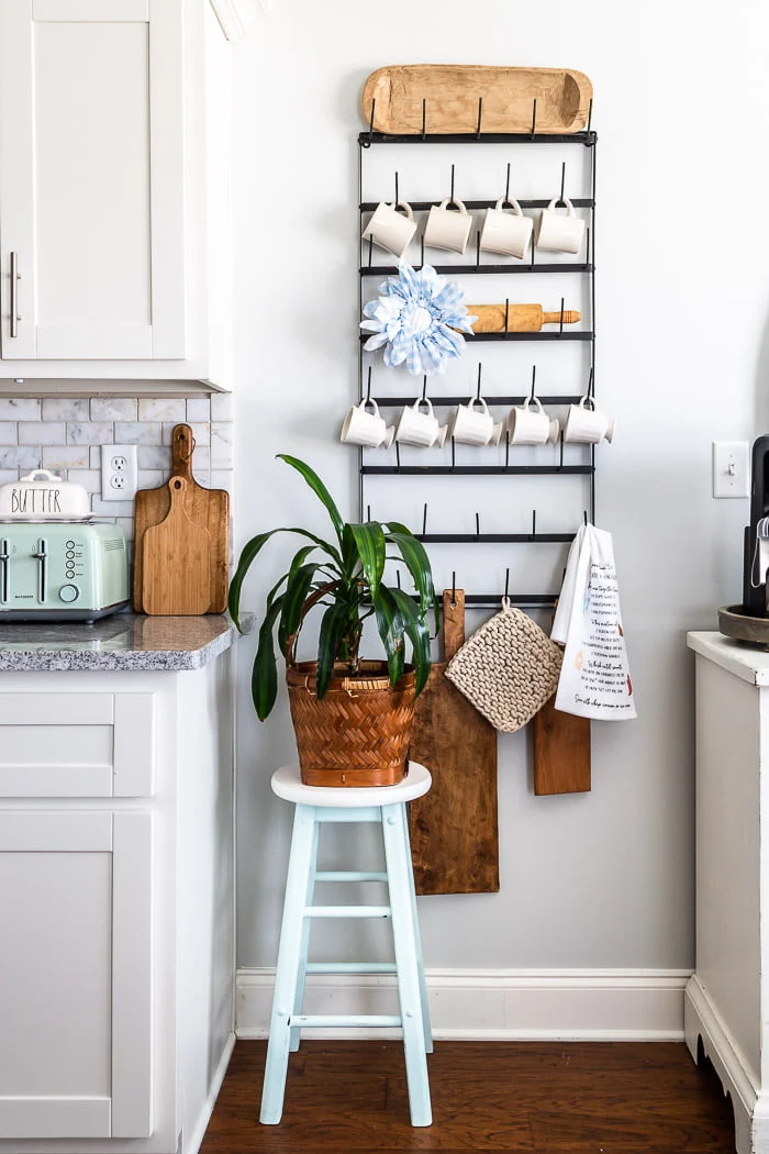 white cabinets, black mug rack, wood boards, plant, fabric flower