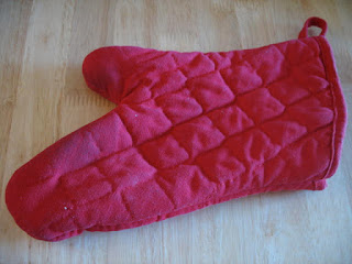 Red Glove Oven Mitt on a wooden cutting board