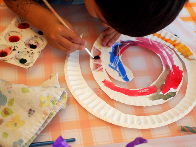 boy using liquid watercolors to paint paper plate snakes