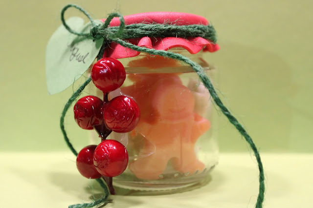 Frasco, decorado com bolas vermelhas de azevinho, com sabonetes em forma de motivos de Natal