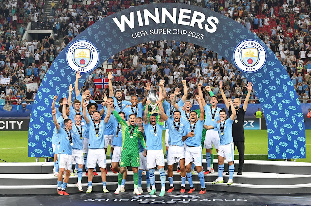 MANCHESTER CITY F. C. Temporada 2023-24. Los jugadores del Manchester City celebran su primer título de la Supercopa de Europa. MANCHESTER CITY F. C. 1 🆚 SEVILLA F. C. 1 En los penaltis: MANCHESTER CITY FC 5 🆚 SEVILLA FC 4 Miércoles 16/08/2023, 21:00 horas. 48ª edición de la Supercopa de Europa. El Pireo, Atenas, Grecia, estadio Giorgios Karaiskakis: 29.500 espectadores. GOLES: ⚽0-1: 25’, Youssef En-Nesyri. ⚽1-1: 62’, Cole Palmer. PENALTIS: ⚽1-0: Erling Haaland, gol. ⚽1-1: Lucas Ocampos, gol. ⚽2-1: Julián Álvarez, gol. ⚽2-2: Rafa Mir, gol. ⚽3-2: Mateo Kovačić, gol. ⚽3-3: Ivan Rakitić, gol. ⚽4-3: Jack Grealish, gol. ⚽4-4: Gonzalo Montiel, gol. ⚽5-4: Kyle Walker, gol. ❌5-4: Nemanja Gudelj, se estrella en el larguero.