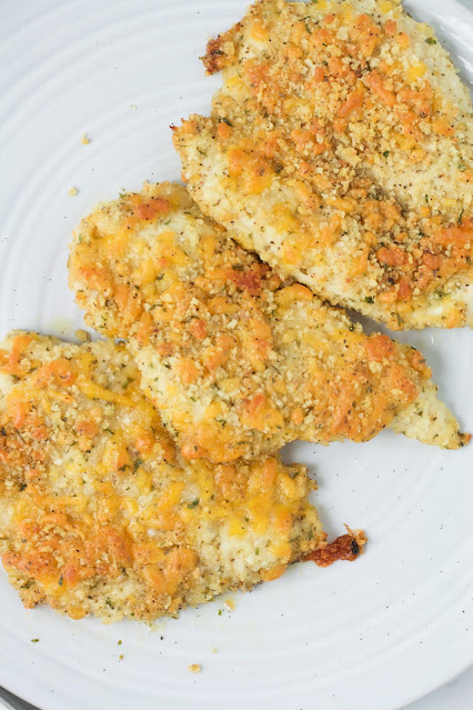 cheesy chicken lined up on a white platter.