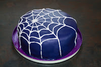 3 layer lemon cake covered with navy icing and iced with a white spiderweb