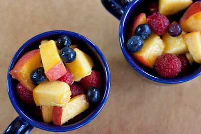 Cups of fruit salad with peaches, blueberries, and raspberries