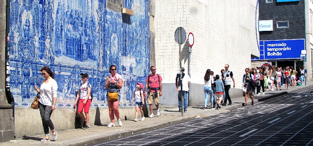 Pessoas circulando ao lado da Capela das Almas próximo à entrada do Mercado Temporário do Bolhão