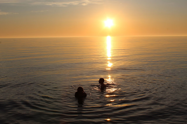 Kids swimming at sunset