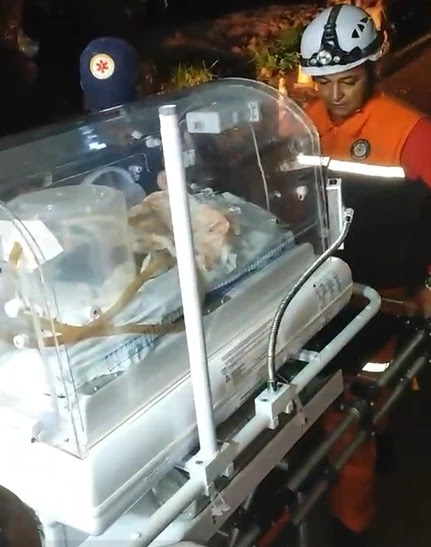 Socorristas atravessam trecho cortado da BR-222 com incubadora e bebê nos braços no Maranhão