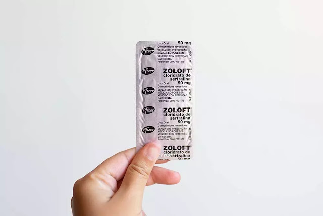 hand holding up zoloft pills in package