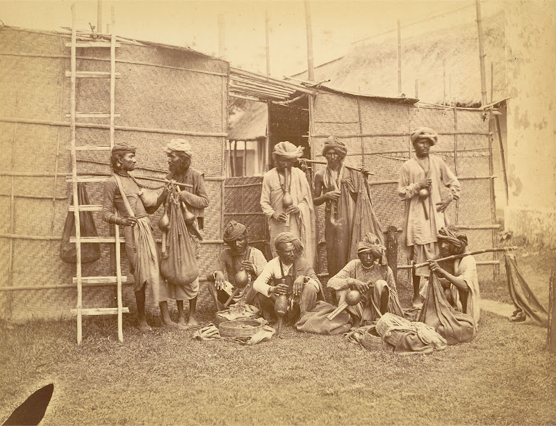 Portrait of Nine Snake Charmers Posed with their Pipes, Baskets and Sacks Containing the Snakes - Eastern Bengal 1860's