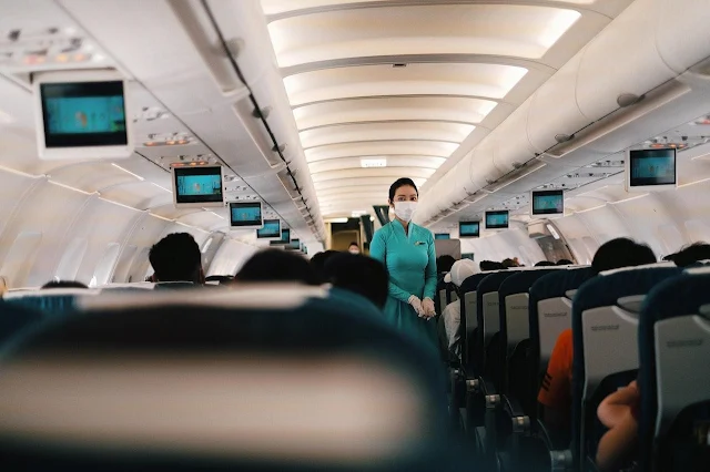 A flight attendant standing in between the row seats on a plane