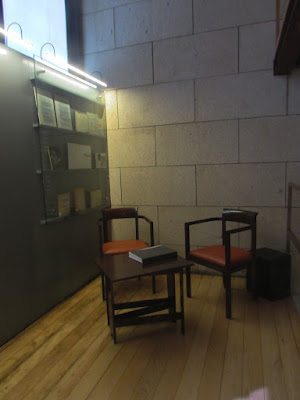 duas cadeira uma mesa de centro com um livro e uma estante com vários livros