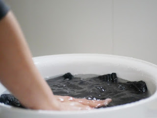 湯おけ（洗面器）を使ってカシミヤニットを押し洗いしているイメージ写真