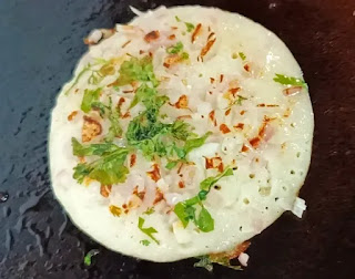 onion uttapam topped with onion and coriander leaves