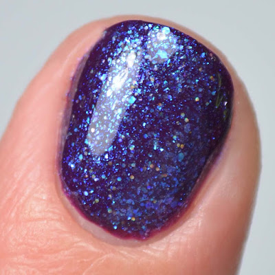 blue fleck nail polish topper swatched over purple close up