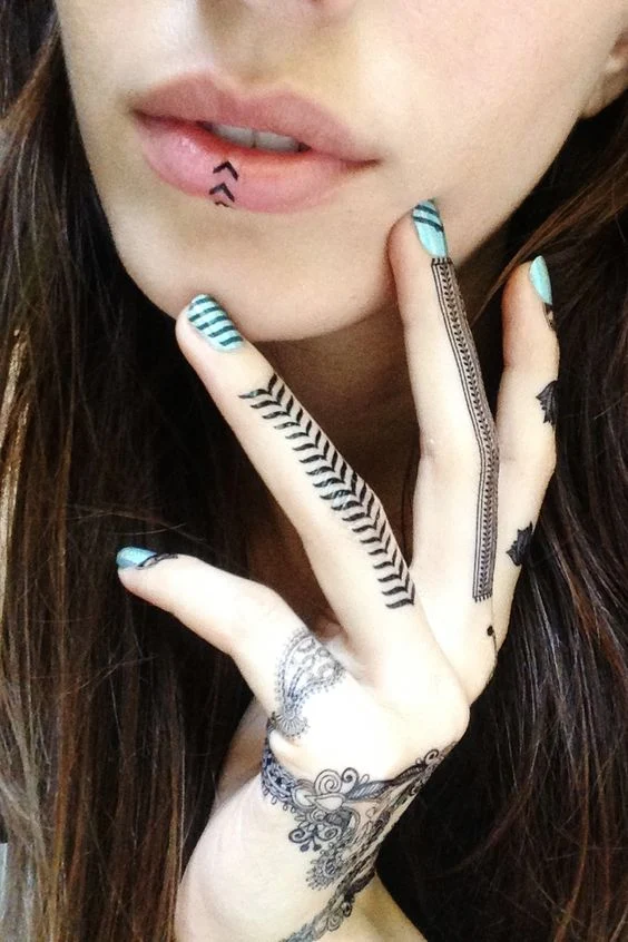 imagen de una modelo tocándose la cara, lleva tatuajes de henna en los dedos