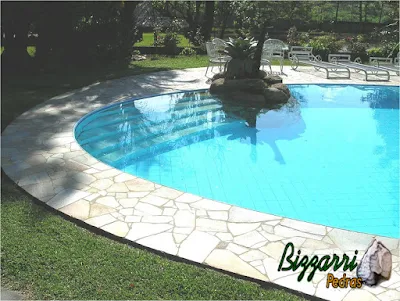 Construção da piscina de alvenaria com cascata de pedra com pedras ornamentais e o piso com pedras Luminárias.